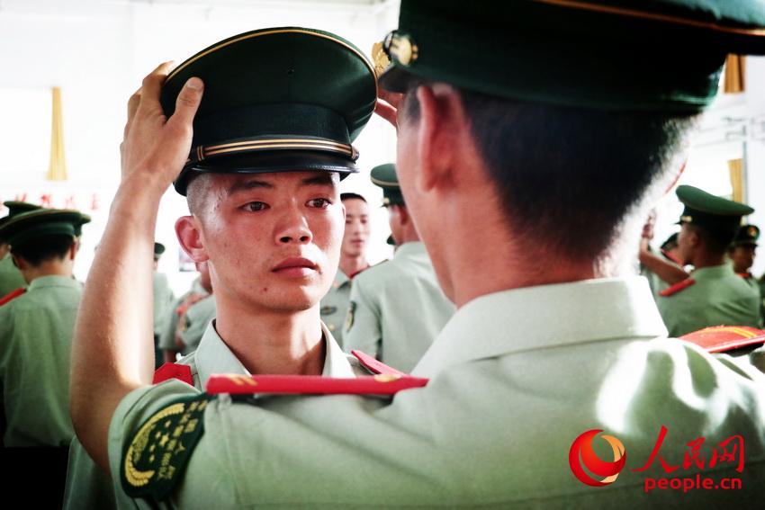留队官兵为战士摘下帽徽。